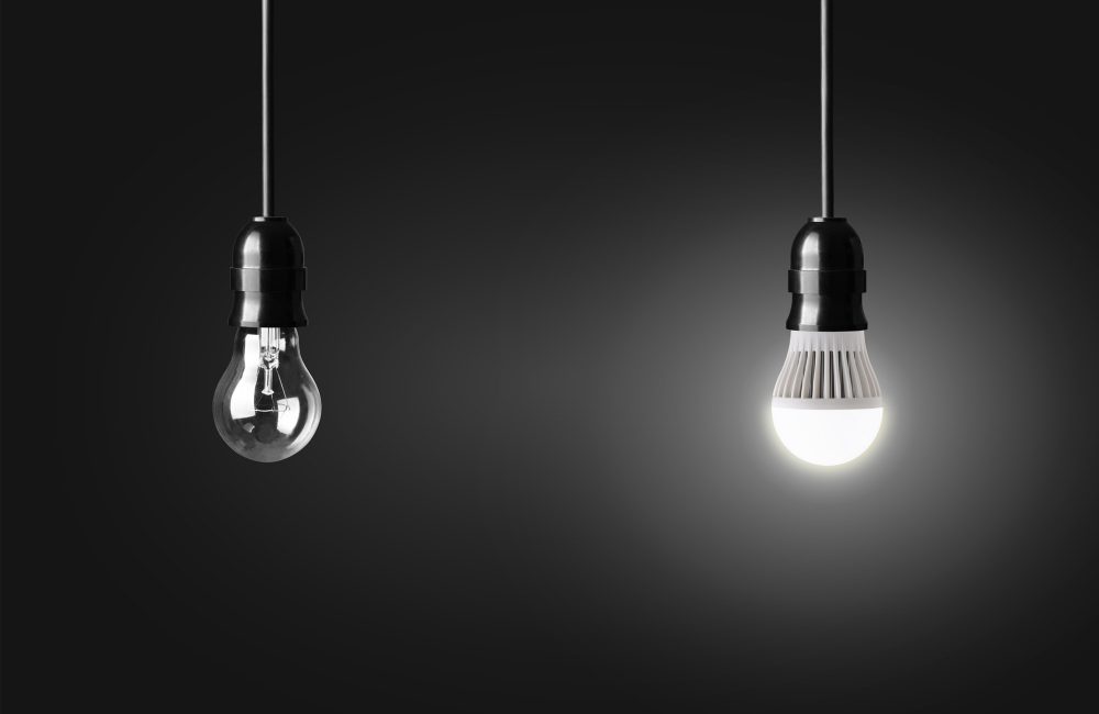 Light bulb and glowing LED bulb on black